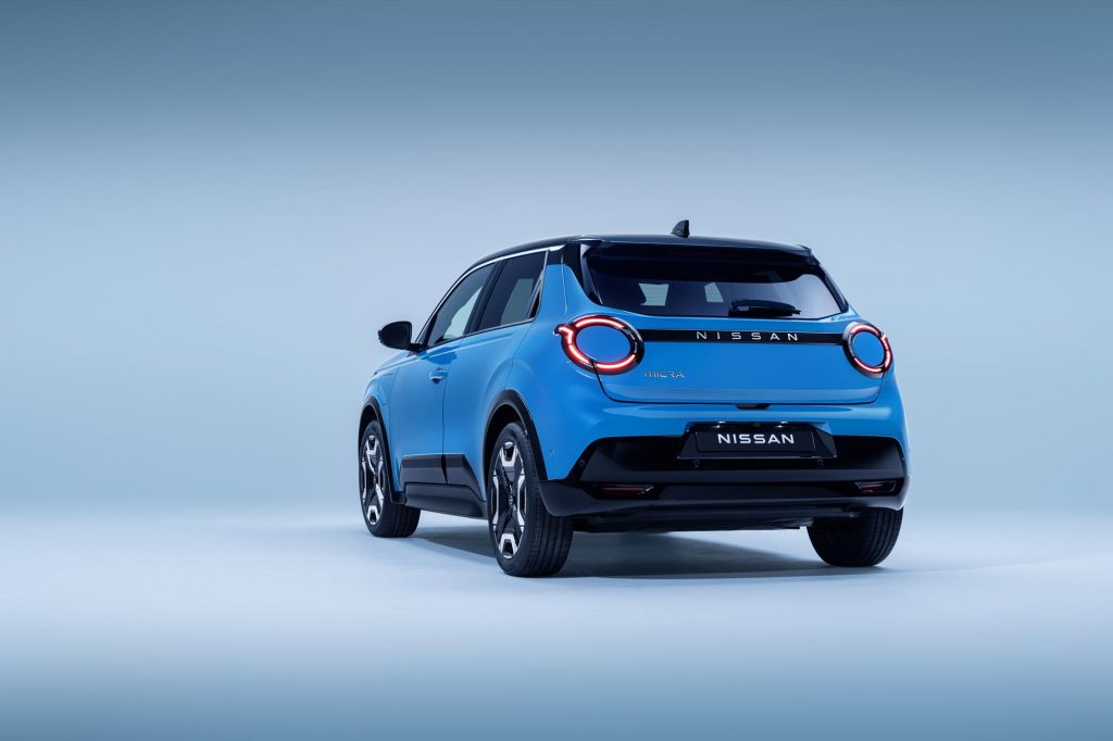 4 view of Micra in blue gear color showing signature lit headlamps. nissan name plate, driver & passenger doors, wheels, and black bumper